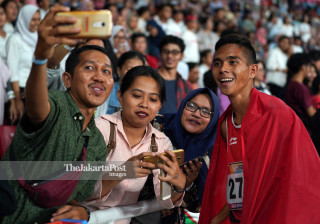 Atlet Para Atletik putra Indonesia Pradana melakukan swafoto dengan para supporter
