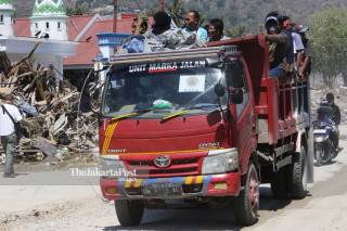 Pekerja bangunan menggunakan kendaraan milik BNPB saat melintas di Jalan Diponegoro Palu Sulawesi Tengah