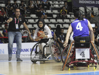 Pebasket kursi roda putri Afganistan Bayat Nilofar (kedua kiri) berusaha melewati hadangan pebasket kursi roda Thailand.